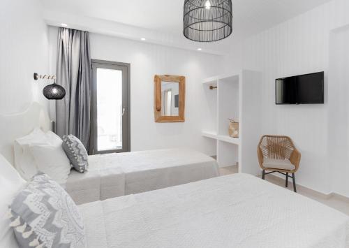 a white bedroom with two beds and a tv at BLUE SEA Naxos in Stelida