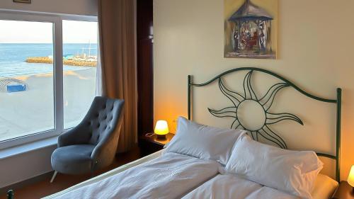 a bedroom with a bed and a chair and a window at ElStefanino House in Eforie Nord