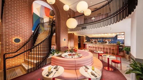 a restaurant with tables and chairs and a staircase at Hotel Indigo Adelaide Markets by IHG in Adelaide
