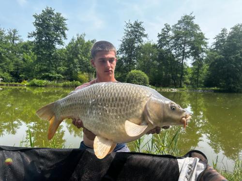 a man holding a large fish in front of a lake at Cabane insolite in Saint-Victor-de-Morestel