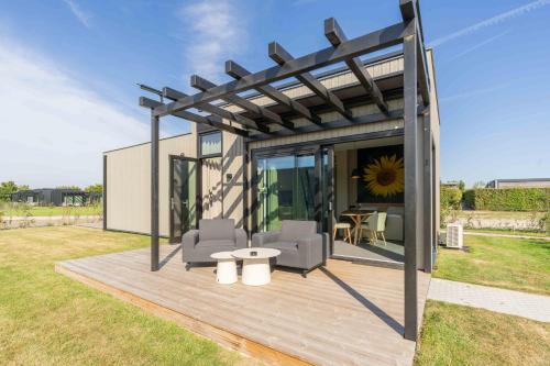 a pavilion with chairs and a table on a deck at Buitenplaats Hotel met terras, studio in Ellemeet