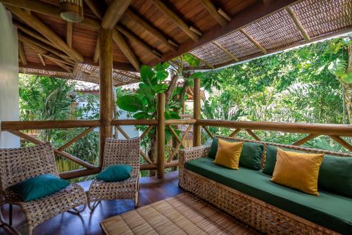 a pergola with a couch and chairs on a porch at Pousada Cajueiro Trancoso in Trancoso