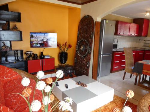 a kitchen with red cabinets and a white table in a room at Villa Charlestine in Yaoundé