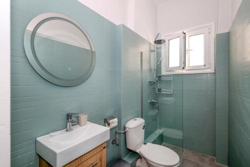 a bathroom with a sink and a mirror and a toilet at Muse Studios & Apartments Aegina in Agia Marina Aegina