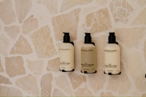 three bottles of hair products sitting on a wall at Villa Gufo in Ostuni