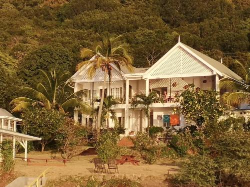 a white house with a palm tree in front of it at Green Roof Inn in Carriacou