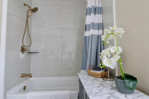 a bathroom with a white tub and a shower with a vase of flowers at Mod Abode 2 bdrm Highland UofR Downtown in Rochester