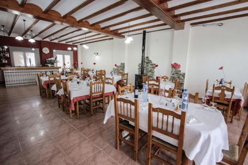 a dining room with white tables and wooden chairs at El Tossal in El Castell de Guadalest