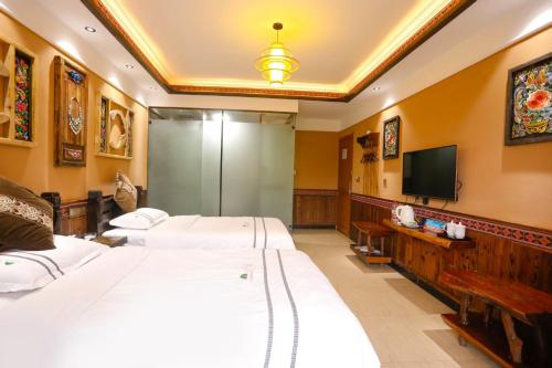 a bedroom with three beds and a television at Huaqianshu Theme Inn in Wang-ts'un