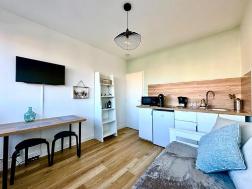 a living room with a table and a kitchen at Le petit chartreux in Grenoble