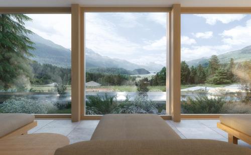 a room with a large window with a view of the mountains at Suvretta House in St. Moritz
