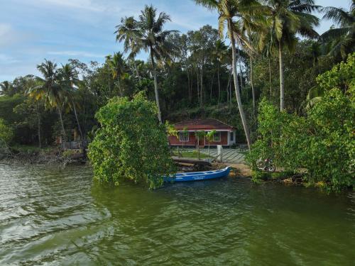 a boat in the water next to a house at Anoop's Lake View Cottage -2BHK in Munroe Island