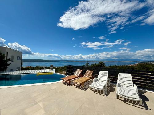 Un grupo de tumbonas y una piscina. en Villa V, en Crikvenica