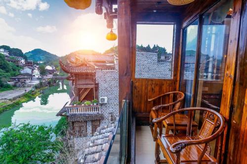 a balcony with two chairs and a view of a river at Huaqianshu Theme Inn in Wang-ts'un