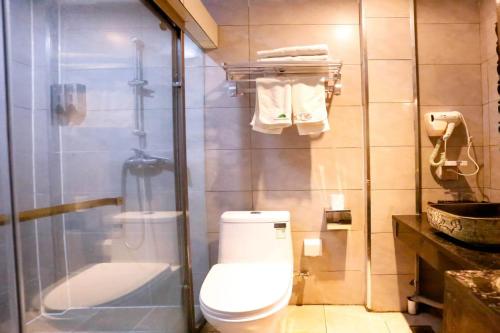 a bathroom with a toilet and a shower with towels at Huaqianshu Theme Inn in Wang-ts'un