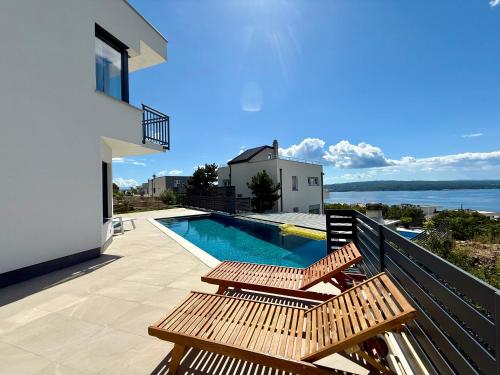 un balcón con 2 bancos y una piscina en Villa V, en Crikvenica