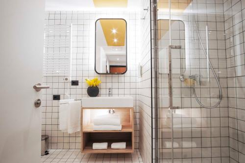 a white tiled bathroom with a sink and a shower at Aparthotel Colombo Roma in Rome