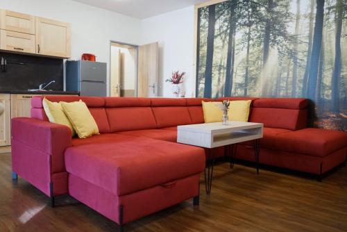a living room with a red couch and a table at Apartmán Antýgl - ubytování s domácími mazlíčky in Modrava