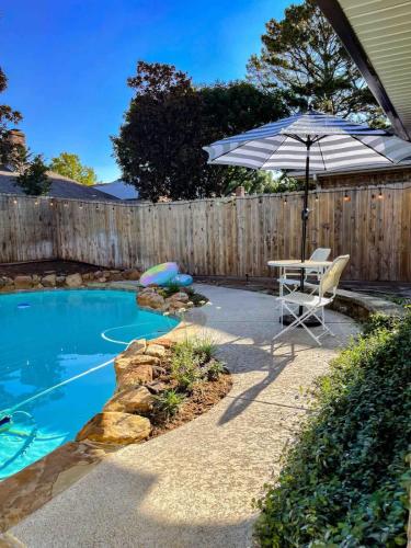a patio with a table and an umbrella next to a pool at Luxe 4BR with Heated Pool and Hot Tub - Walk to Lake in Grapevine