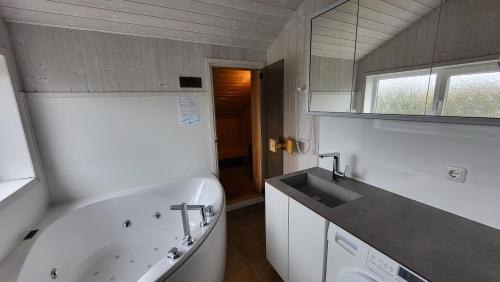Un baño con bañera blanca y lavabo. en Ferienhaus Möwenstübchen Grömitz, en Grömitz