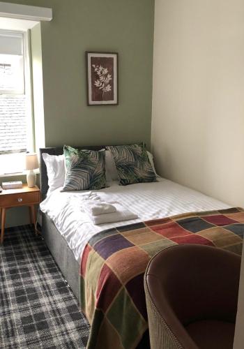 a bedroom with a bed with a blanket on it at The Rhu Inn in Rhu