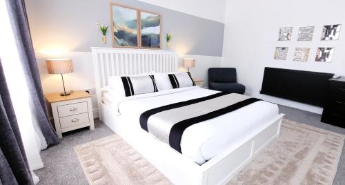a bedroom with a large white bed and a chair at Wigan Central Executive Apartments I Family Rooms I Free Parking in Wigan