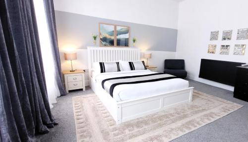 a white bedroom with a bed and a chair at Wigan Central Executive Apartments I Family Rooms I Free Parking in Wigan
