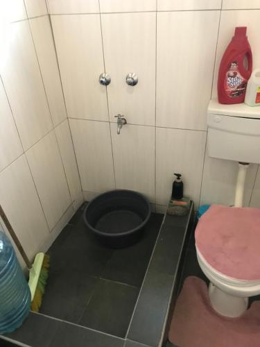 a bathroom with a toilet and a black bucket at Homely Stay in Livingstone