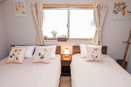 two beds in a room with a window at Ohanachaya station 5-minute walk 4ldk house maxi 9people family friendly in Tokyo