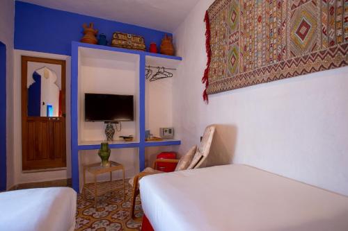 a bedroom with a bed and a tv and a chair at Riad Alia Suites SPA in Chefchaouene