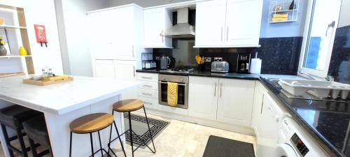 a kitchen with white cabinets and a counter with stools at Wigan Central Executive Apartments I Family Rooms I Free Parking in Wigan