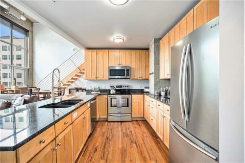 a kitchen with wooden cabinets and a stainless steel refrigerator at Stylish City Loft Walk To Dining & Shops in Denver