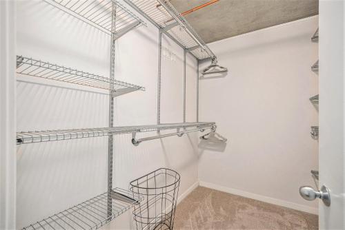 a walk in closet with white walls and metal shelves at Stylish City Loft Walk To Dining & Shops in Denver