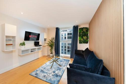 a living room with a black couch and a window at Chelsea Thames View Suite in London