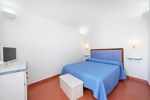 a bedroom with a blue bed and a tv at Wonderful villa with swimming pool overlooking the sea, 200 steps from the road in Conca dei Marini