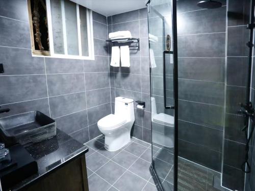 a bathroom with a toilet and a glass shower at Huaqianshu Theme Inn in Wang-ts'un