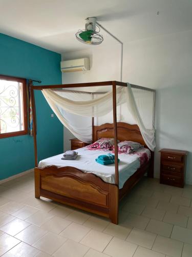 a bedroom with a wooden bed with a canopy at Villa Warang in Mbour
