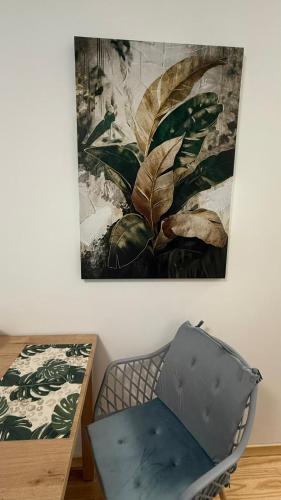 ein Gemälde, das an einer Wand neben einem Stuhl hängt in der Unterkunft Green Leaf Studio in Breslau