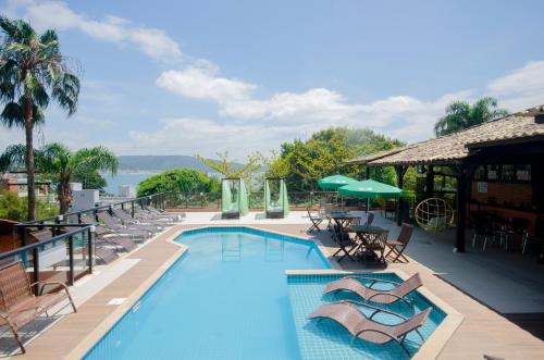 a swimming pool with lounge chairs and a resort at Pousada Palmeiras Bombinhas in Bombinhas