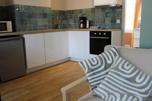 a kitchen with white cabinets and a black appliance at La Bullote - Gîtes - Paris Roissy CDG in Villeneuve-sous-Dammartin