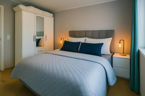 a bedroom with a large bed with blue pillows at Northern Lights Apt Midtgaard, Kvaløya Tromsø Modern 2BR, Free Parking in Tromsø