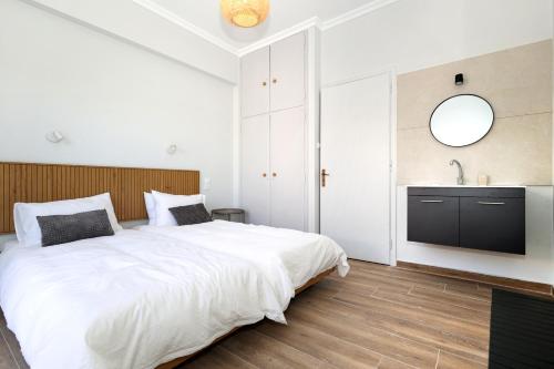 a white bedroom with a large bed and a sink at Muse Studios & Apartments Escape in Agia Marina Aegina
