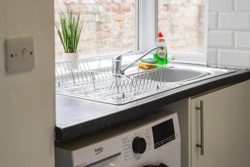 a kitchen sink with a dish drying rack next to a window at Cosy Home in Grimsby Town Centre in Grimsby