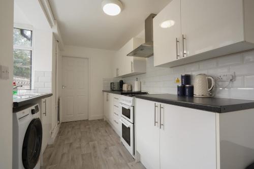 a kitchen with white cabinets and a washer at Cosy Home in Grimsby Town Centre in Grimsby