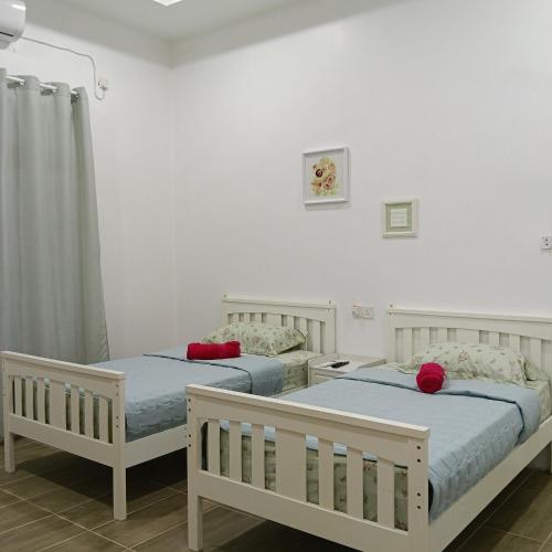 two beds in a room with white walls at Lu&Lu Rooms & Homestay in Dungun