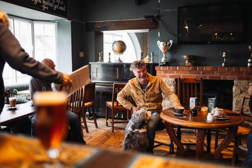 a man sitting at a table with a dog in a restaurant at The Rose & Crown, Ashbury in Ashbury