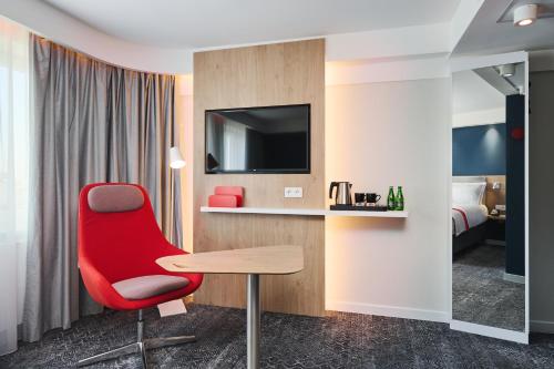 a hotel room with a red chair and a desk at Holiday Inn Express Lublin by IHG in Lublin