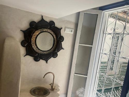 un miroir accroché au mur à côté d'un lavabo dans l'établissement Dar Sarsar Artistic Music, à Marrakech