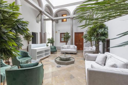 a living room with white furniture and plants at BiBo Suites Palacio de Portago in Granada