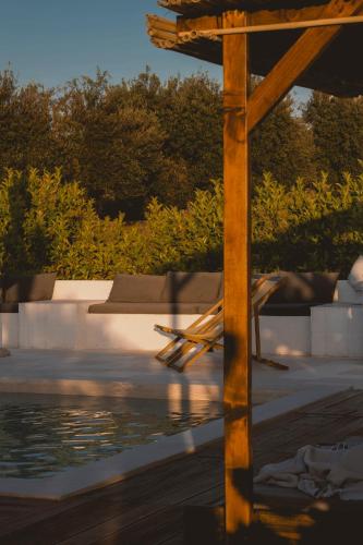 a wooden chair sitting next to a swimming pool at Villa Gufo in Ostuni